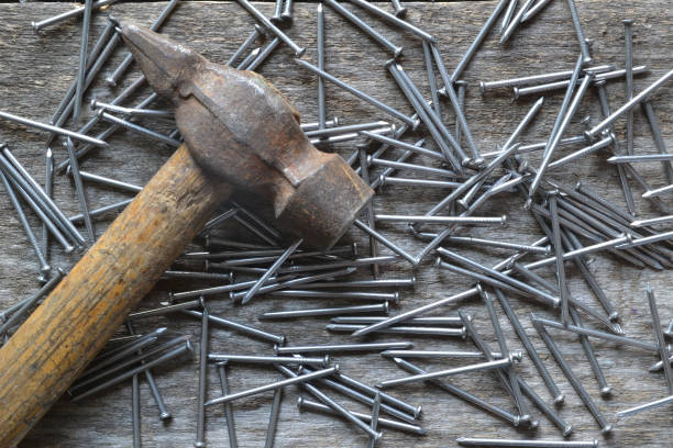 istock Nails and a hammer on an old wooden table. 1006593980