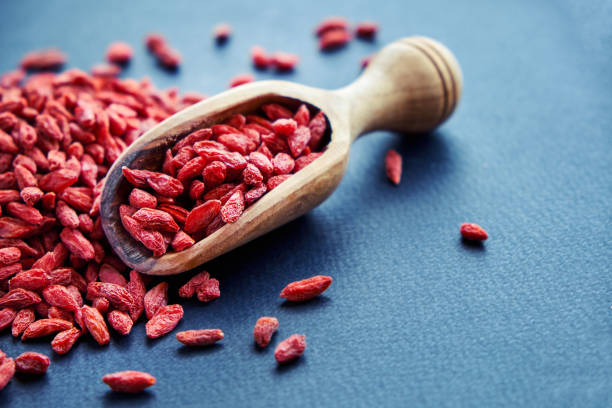Goji in bowl on wood table. Top view of fresh goji in scoop and bowl. Goji in heart shape on table stock photo