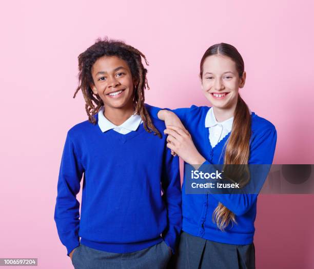 Two Students Standing Togehter Stock Photo - Download Image Now - Colored Background, Teenage Boys, Teenage Girls