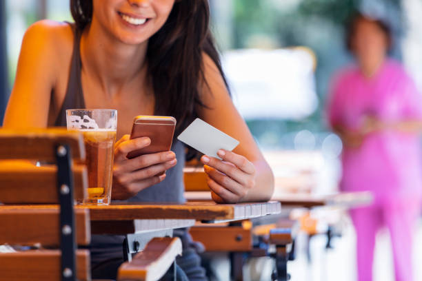istock Young woman at cafe using credit card for online transaction 1006597890