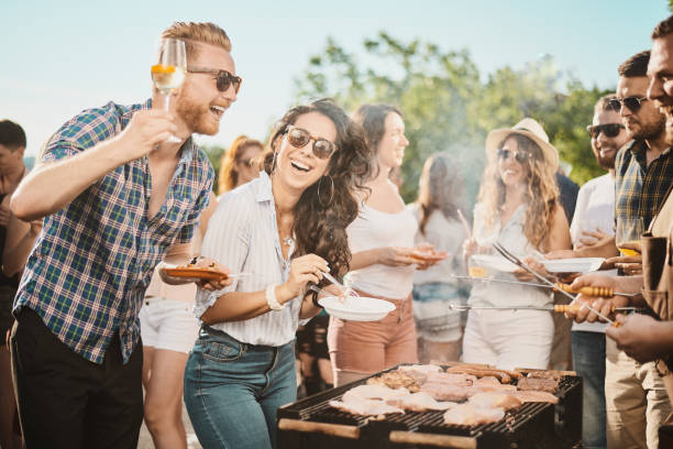 istock Group of people standing around grill. 1006597924
