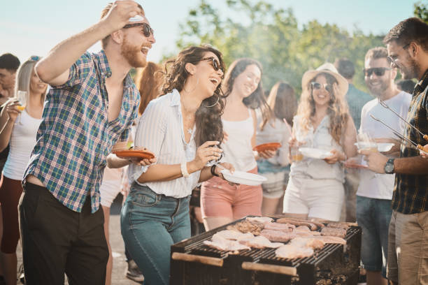 istock Group of people standing around grill. 1006598276