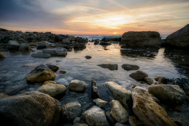 paysage au lever du soleil avec rock et eaux calmes contre ciel vibrant. - long exposure rock cloud sky photos et images de collection