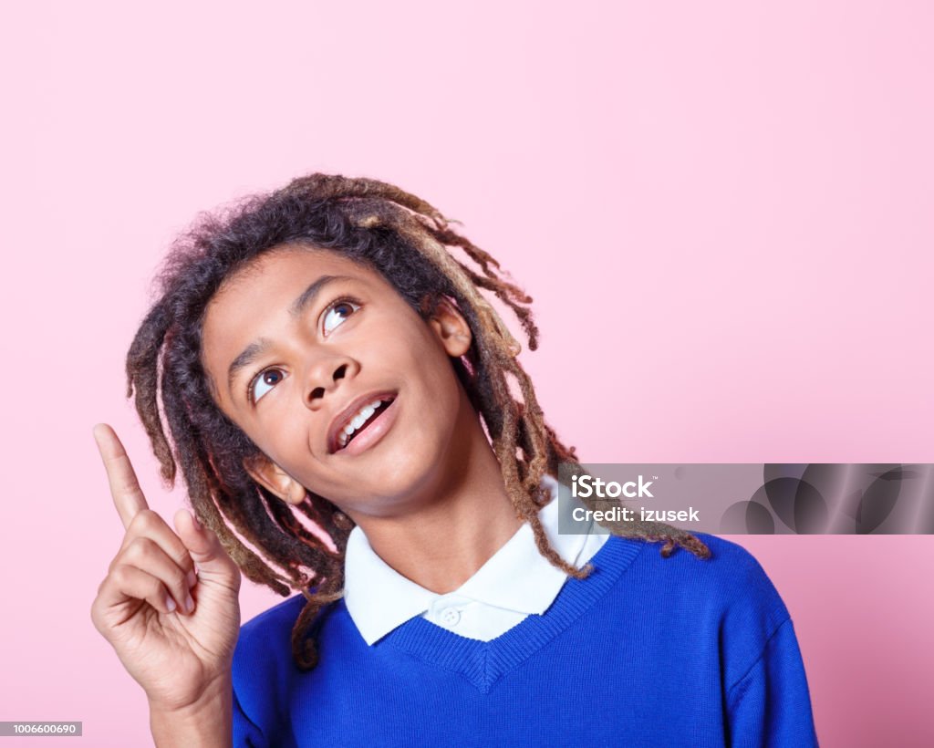 School boy with an idea Close up portrait of young afro american school boy thinking of an idea over pink background Boys Stock Photo