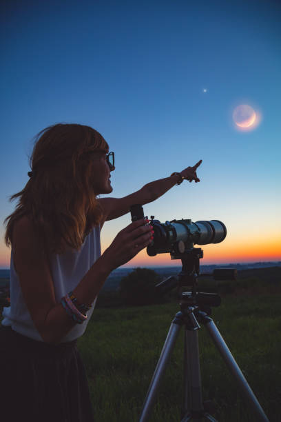 istock Girl looking at lunar eclipse through a telescope. My astronomy work. 1006605600