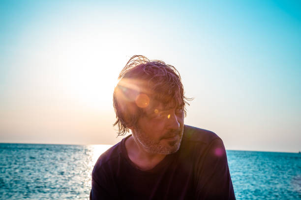 Portrait of good looking middle aged man on the beach while sunsets