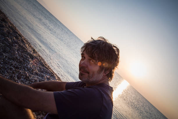 istock Handsome man relaxing on the beach in Greece while sunsets 1006607530