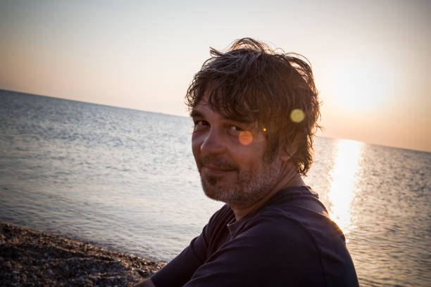 istock Handsome man relaxing on the beach in Greece while sunsets 1006607616