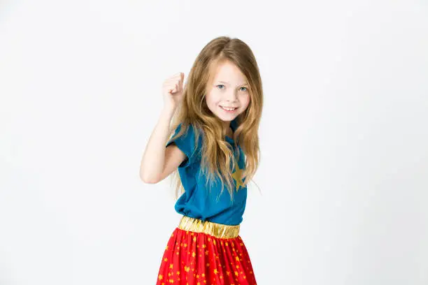 young, blond girl is dressed as a supergirl in the studio