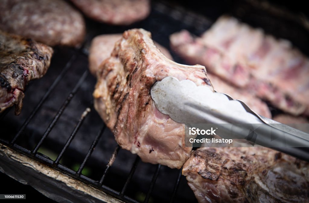 turning over ribs Pair of tongs turning over ribs over the grill Barbecue - Meal Stock Photo