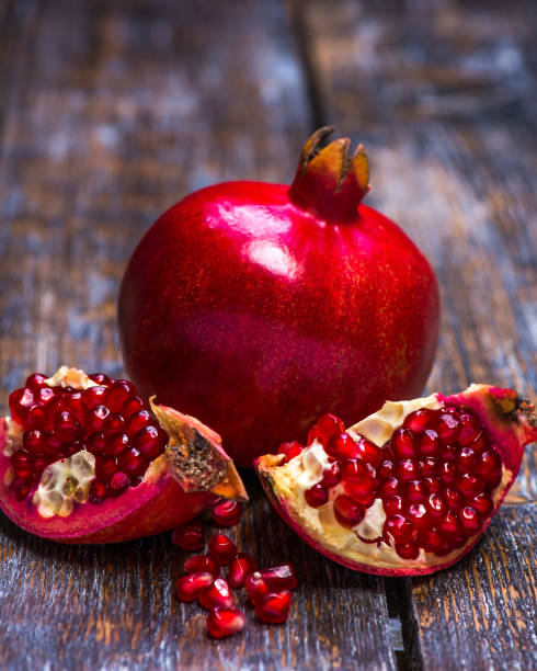istock Ripe red pomegranate fruit on a wooden background. Close-up 1006616118