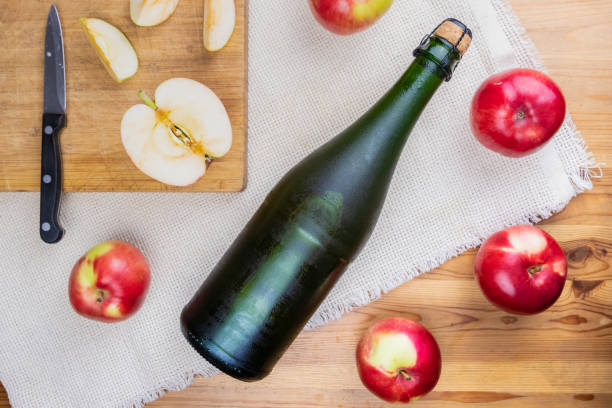 plano coloca com garrafa gelada refrigerado arrolhado cidre na mesa de madeira rústica - corked - fotografias e filmes do acervo