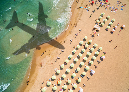 Aerial view airplane shadow and beach with umbrellas