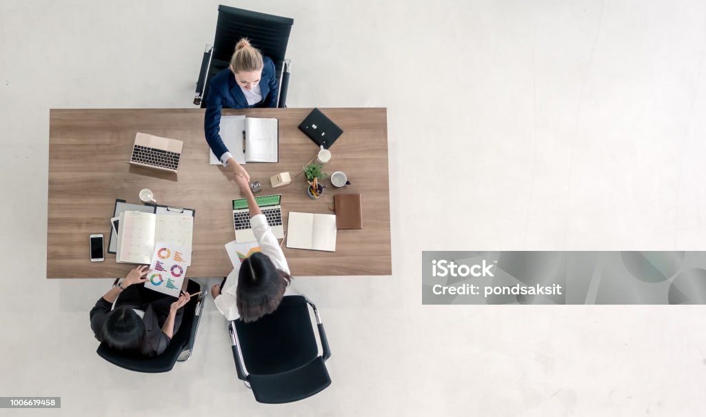 Top view of business people shaking hands Top view of business people shaking hands after sealing a deal. High angle view of casual businesswomen handshake after concluding business agreement. Financial Advisor Stock Photo