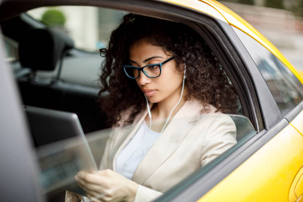 istock Young businesswoman using digital tablet in a taxi 1006620576