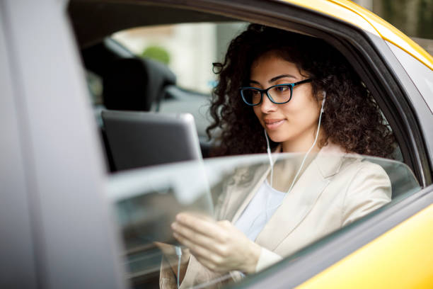istock Young businesswoman using digital tablet in a taxi 1006620630