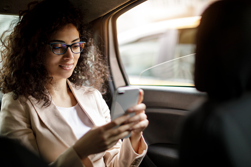 Businesswoman using smart phone in a car
