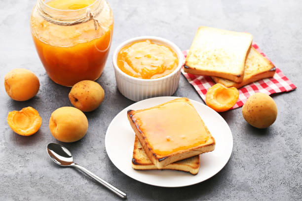 istock Apricot jam in bowl with bread toasts on grey wooden table 1006624002