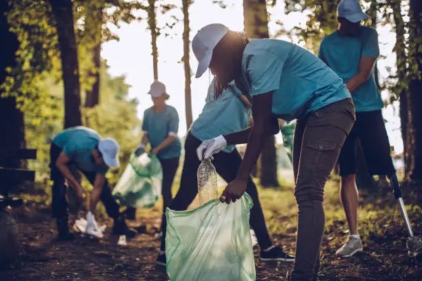 Group of multi-ethnic people, people with differing abilities , volunteers with garbage bags cleaning park area