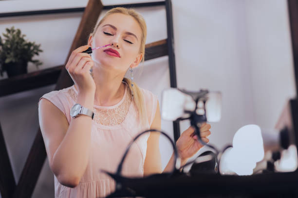 istock Blonde-haired makeup artist smelling her new lip gloss 1006641414