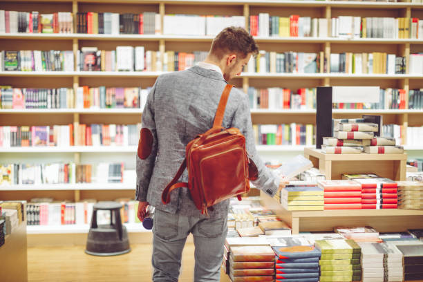 junger mann einkaufsbücher - bookstore stock-fotos und bilder