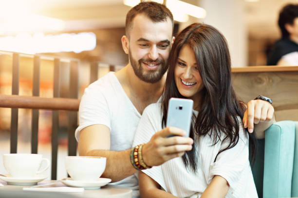 istock Romantic couple dating in cafe and using smartphone 1006641670