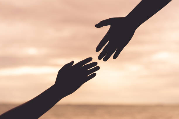 istock silhouette helping hands on blurred sea and sky background. Friendship Day concept. 1006642140