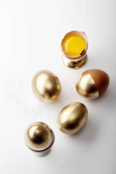 istock Eggs painted golden with yolk in egg stand on white background. Easter concept, copy space 1006645770