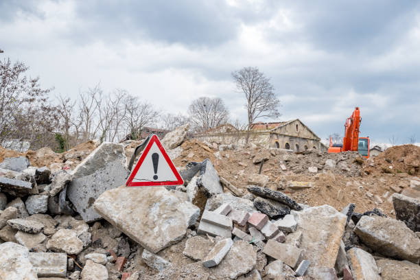 istock Red traffic triangle warning sign stands in front of destroyed building 1006648290