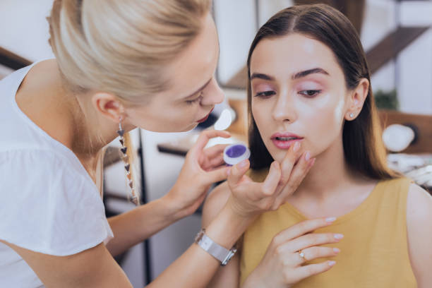 istock Professional blonde-haired makeup artist coloring lips of client 1006649104