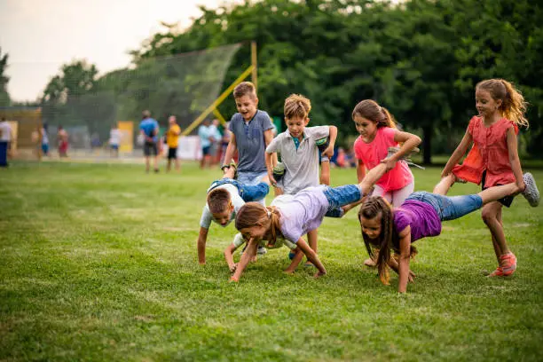 Photo of Group of children playing wheelbarrow race in park