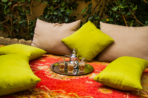 Moroccan mint tea in the traditional glasses on a tray, over a moroccan carpet