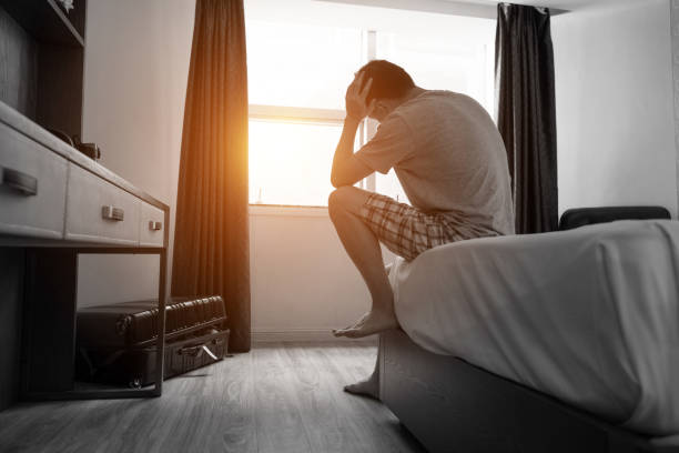 homem sentado na cama com a cabeça nas mãos - bag boredom bored man casual - fotografias e filmes do acervo