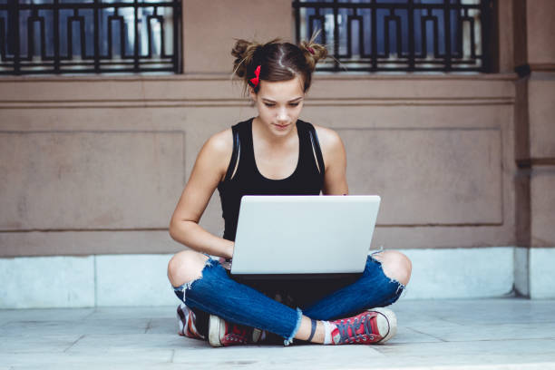 istock Cute caucasian girl using laptop outside 1006665314
