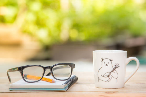 Coffee with milk in coffee cup by white paper and pencil on desk in black and white
