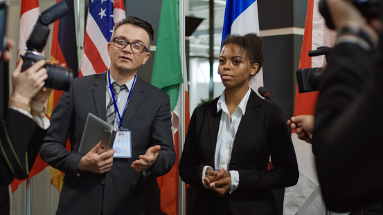 Formal African-American woman talking to journalist for camera and giving interview on international summit