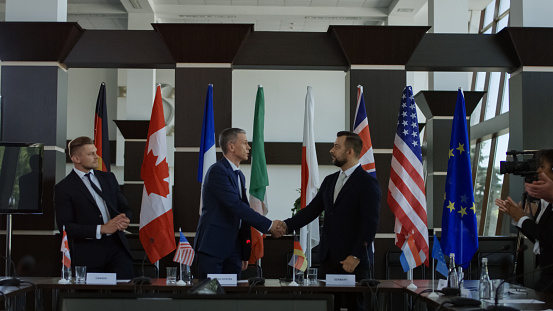 Official representatives shaking hands in agreement on international conference and posing for photo of social media