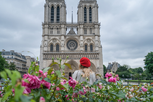 One girl at the Notre Dame de Paris Cathedral in Paris during Springtime in sunny day. People travel discovery city concept\nYoung caucasian woman tourist in Paris