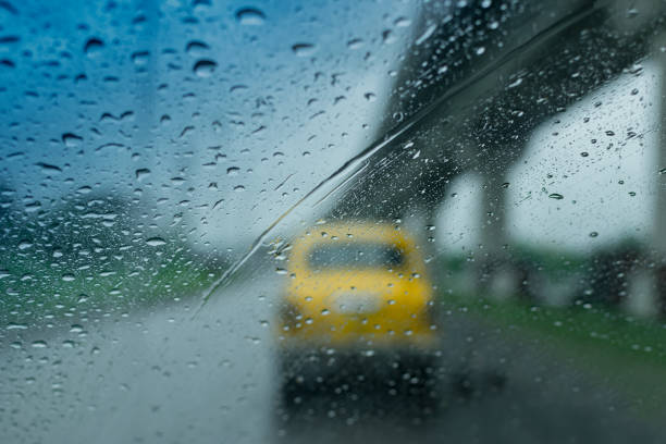 Raindrops falling on glass, abstract blurs - monsoon stock image of traditional yellow taxi of Kolkata (formerly Calcutta) city , West Bengal, India