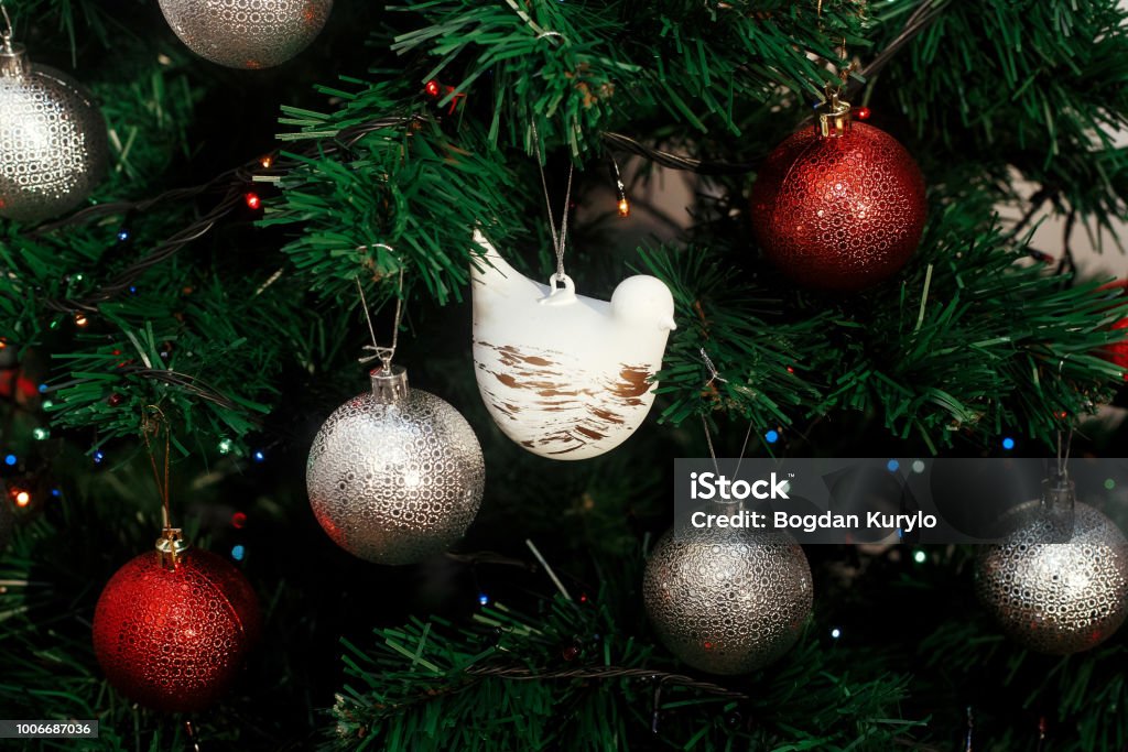 Foto de Enfeites De Natal Prata E Vermelho Pendurado Em Uma Árvore De Natal  Verde Com Luzes Azuis Foco Em Bonito Branco Pomba Decoração De Pássaro e  mais fotos de stock de