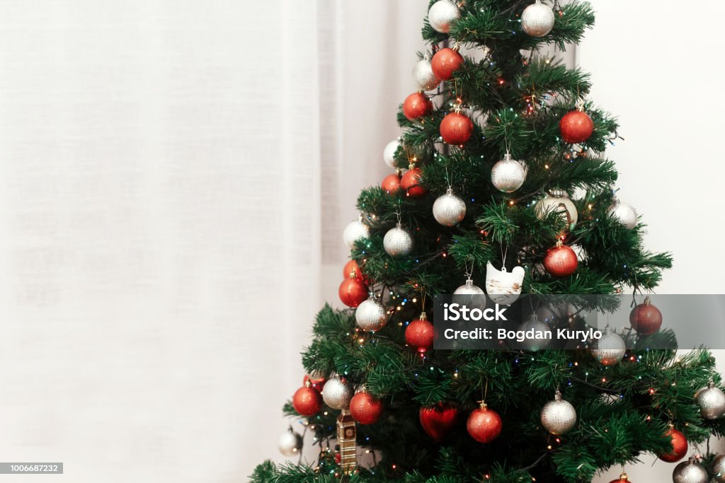 Foto de Enfeites De Natal Colorido Vermelho E Prata Na Árvore De Natal Com  Luzes No Quarto De Luxo Branco Conceito De Cartão De Férias e mais fotos de  stock de Abstrato -