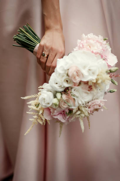 brautstrauß rosa rosen und weißen blüten. braut in der hand hält, mit luxus-ringe auf hintergrund von rosa reichen kleid - cluster verlobungsringe stock-fotos und bilder