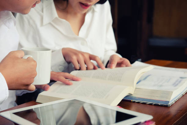 istock Closeup asian woman reading text book and tablet in library. 1006691168