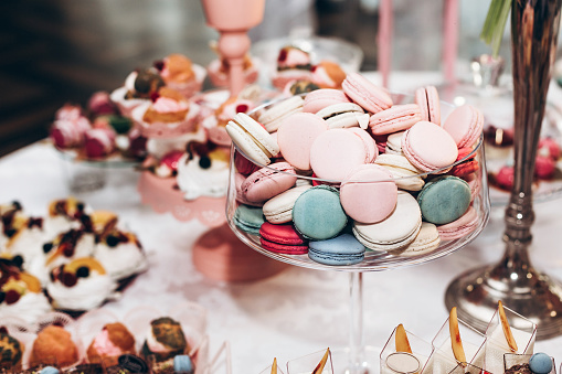 delicious macaroons in glass bowl. candy bar at luxury wedding reception. exclusive expensive catering. table with modern desserts. space for text. baby or bridal shower. holiday celebration