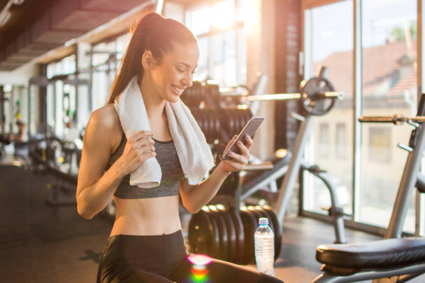 istock Young fit woman using smart phone at gym 1006695078