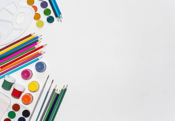 istock Color pencils, paints and brushes on white background. Close up, top view, copy space. 1006696996