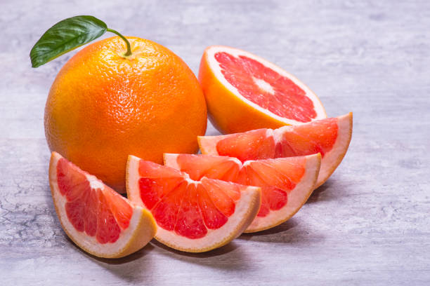 Grapefruit whole, half and pieces ripe, juicy on a gray background