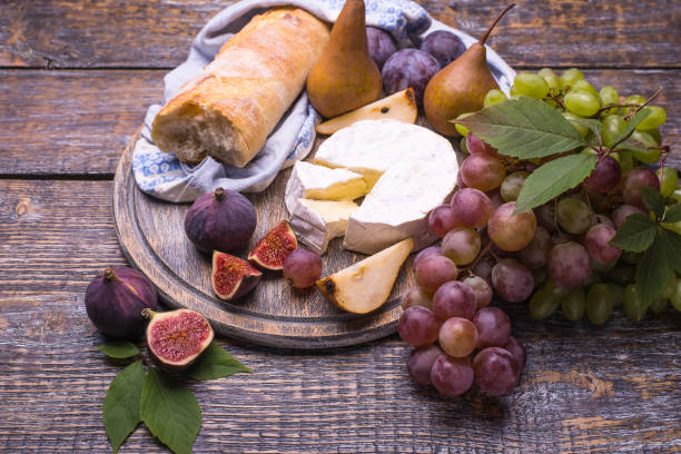 istock The grapes various, figs, plums, pears, white bread, cheese on a wooden table. 1006700514