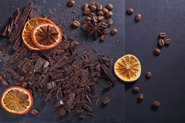 istock Dark chopping chocolate, black roasted coffee beans, dried lemon slices on dark background 1006702528