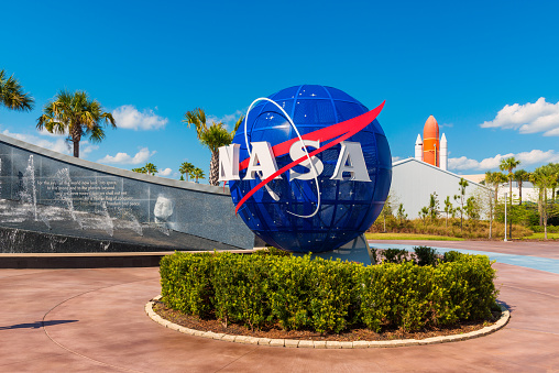 Cape Canaveral, FL, USA - April 1, 2015: NASA Logo on Globe at Kennedy Space Center Visitor Complex in Cape Canaveral, Florida, USA. To the left is a painting visible of President John F. Kennedy.